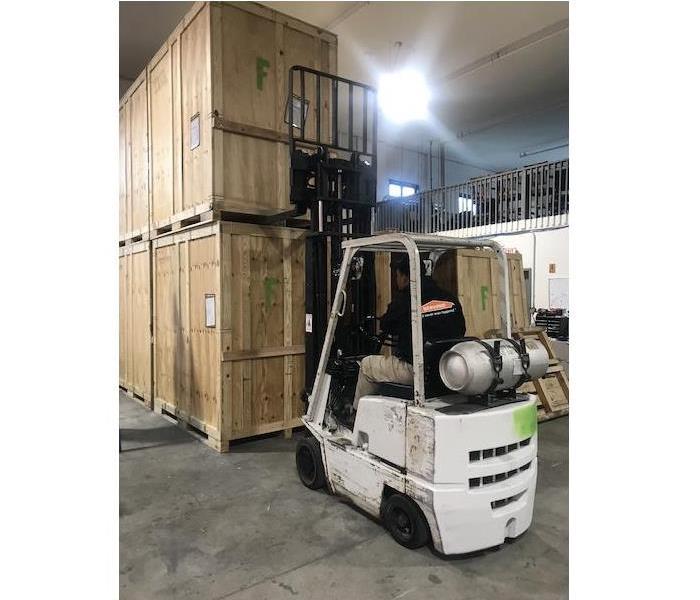 forklift in operation moving stacked, boxed crates in our warehouse